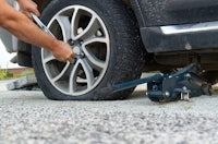 a man putting a tire jack on a car